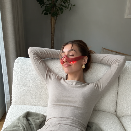 Woman relaxing on the sofa wearing the brick red hands-free eye massager